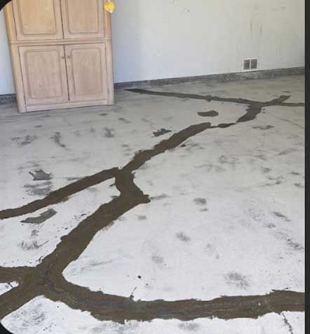 A cracked interior concrete slab with a long split running across it and old adhesive marks.