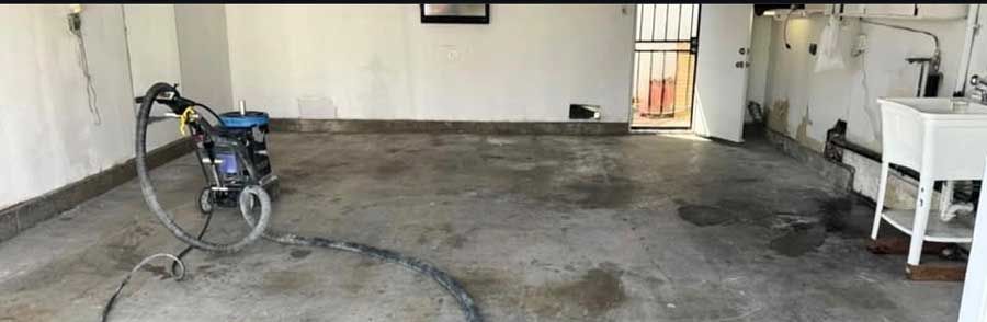 A garage slab mid-preparation, ground back to raw concrete with the grinder still standing on it.