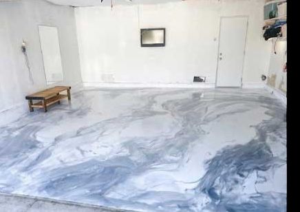 After: the same garage with a white and grey metallic epoxy floor poured across it.